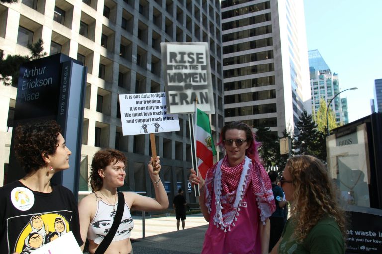 Protest in Vancouver advocating for women's rights in Iran with diverse crowd holding placards.